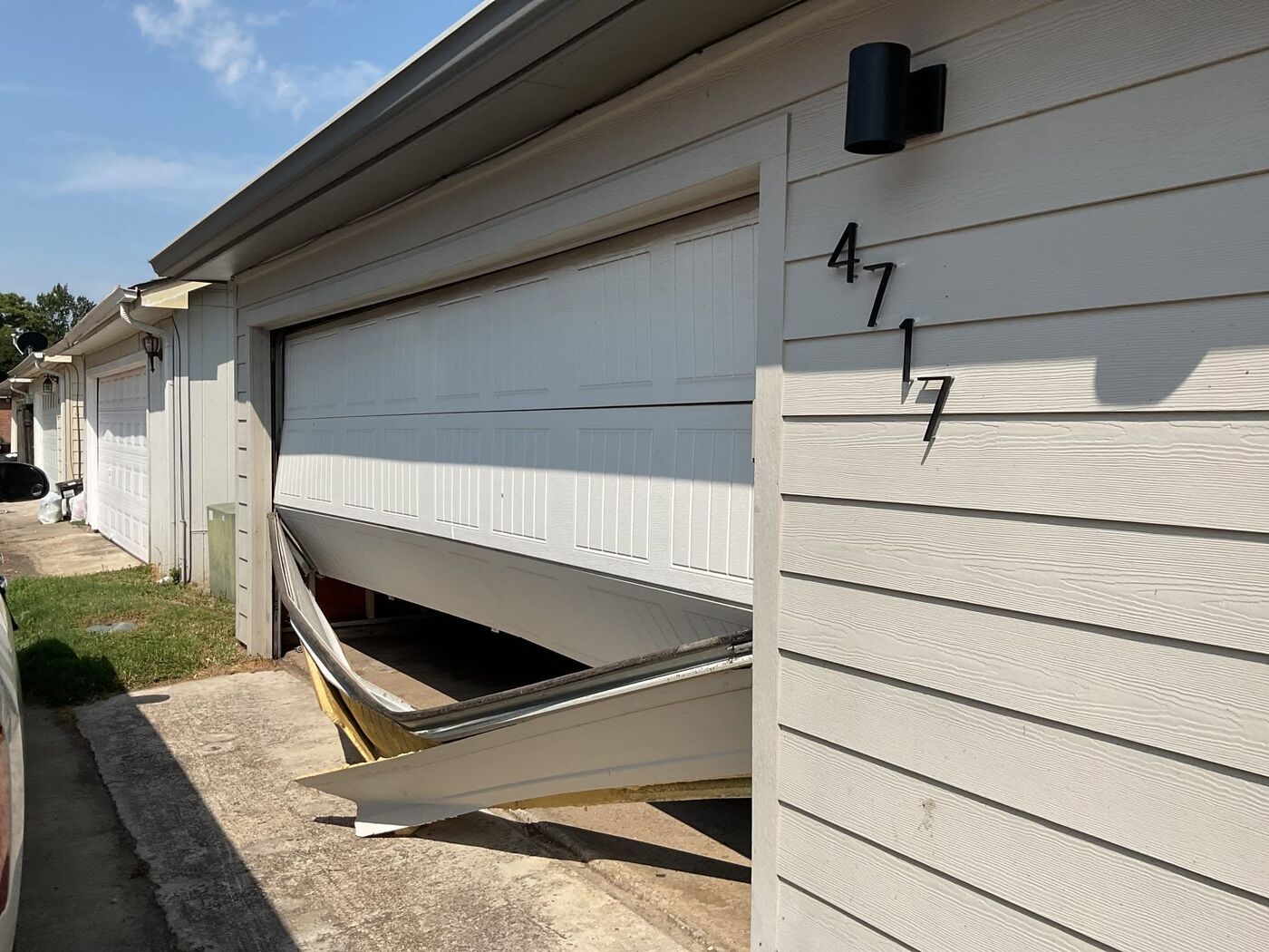 Garage door bent and off its track after a spring failure, needing emergency repair