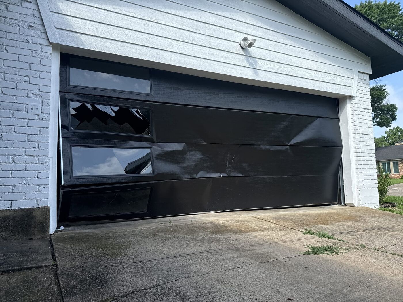 Garage door with broken glass panel insert after storm damage