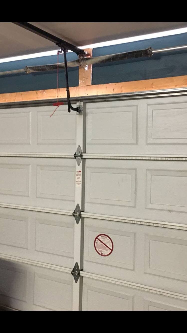 Garage door lift cable and track hardware along the side of a residential door